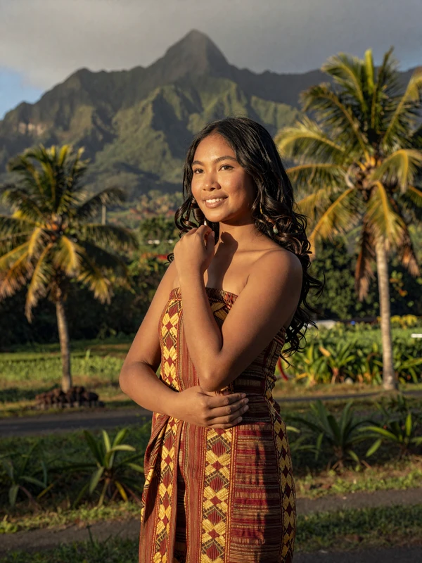 Graceful Timorese woman in traditional tais dress with East Timor mountain landscape